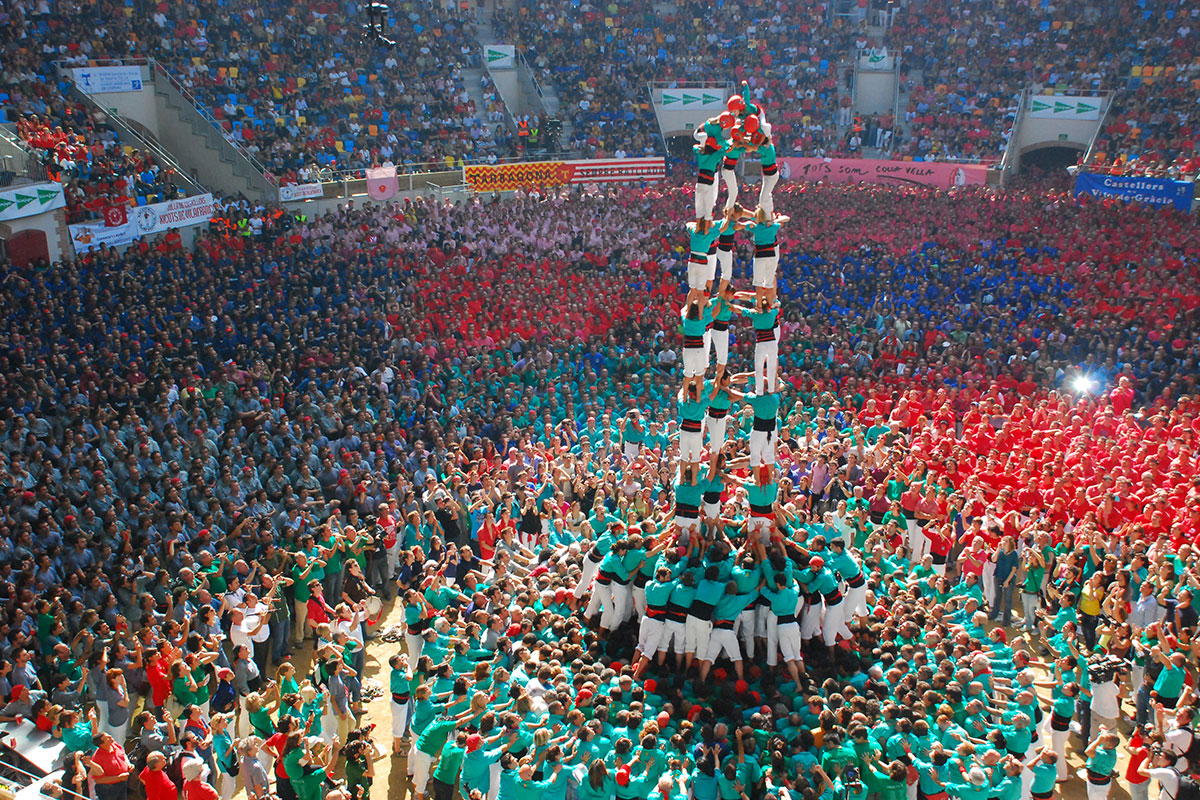 People work together to build tall human towers. This tradition shows teamwork, strength, and community spirit.